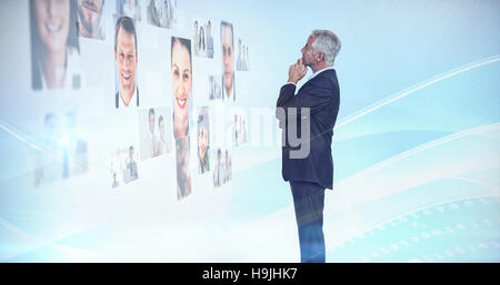 Imprenditore pensieroso guardando una parete ricoperta da immagini del profilo Foto Stock