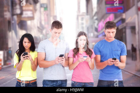 Immagine composita di quattro persone in piedi accanto a ogni altro e scrivere messaggi sui loro telefoni Foto Stock