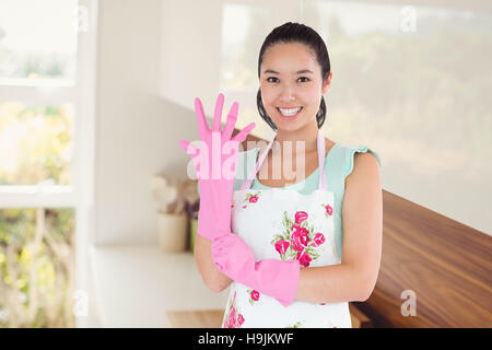 Immagine composita della donna mettendo su guanti di plastica Foto Stock