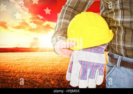 Immagine composita del lavoratore manuale tenendo il casco e guanti Foto Stock