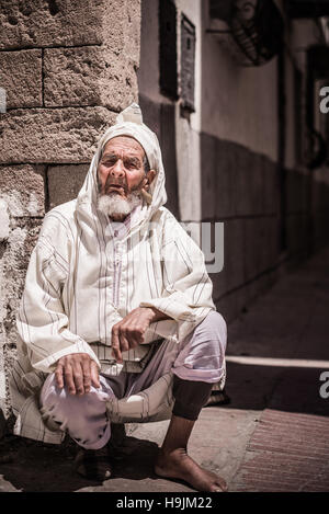 Un ritratto fotografia di un anziano Marocchino tradizionale uomo nella tradizione vestiti seduto in una strada in Marocco, Marrakech Foto Stock