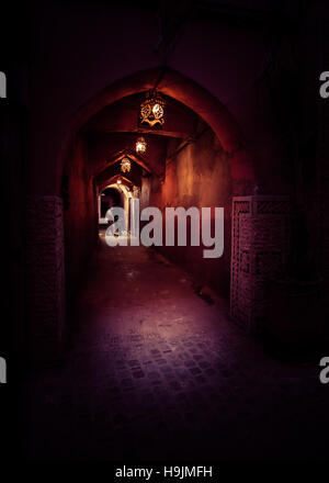 Un marocchino l uomo sta e contempla in un lato oscuro street di notte illuminata da marocchino tradizionale lanterne in Marrakech Foto Stock