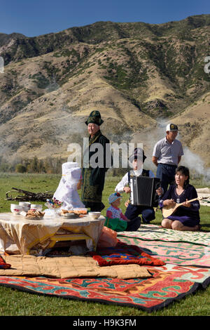 Soggiornare abitanti in abito tradizionale cantare ad un picnic in Chilik river valley Kazakistan Foto Stock