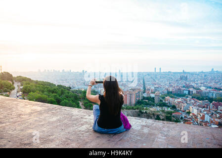 Spagna, Barcellona, donna di scattare una foto di thhe città con il suo smart phone Foto Stock