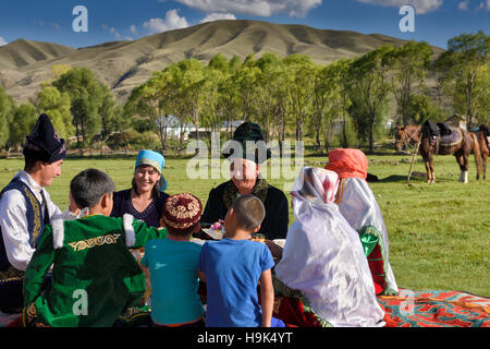 Ridendo famiglia in abito tradizionale ad un picnic in pascolo di Chilik river valley a soggiornare Kazakistan Foto Stock