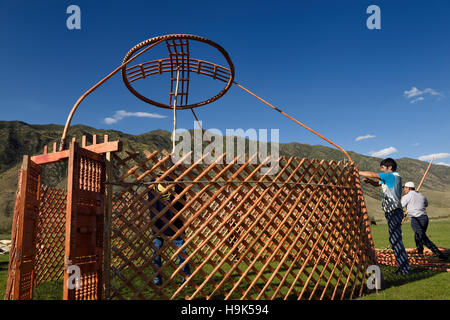 Tre uomini l'impostazione di un telaio yurt in pascolo di Chilik river valley soggiornare Kazakistan Foto Stock