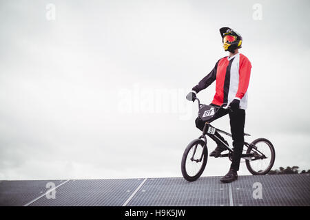 Ciclista in piedi con la BMX bike sulla rampa di partenza Foto Stock