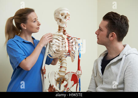 Osteopata a discutere di pregiudizio con il paziente utilizzando lo scheletro Foto Stock