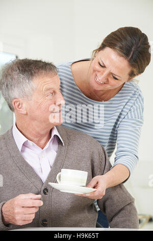 Figlia adulta portando Senior Padre bevanda calda a casa Foto Stock