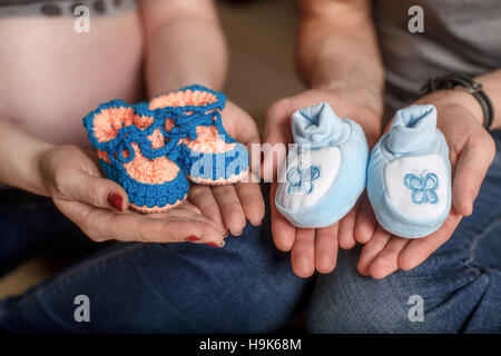 Carino a maglia blu baby scarpine sulle mani. Concetto di gravidanza Foto Stock