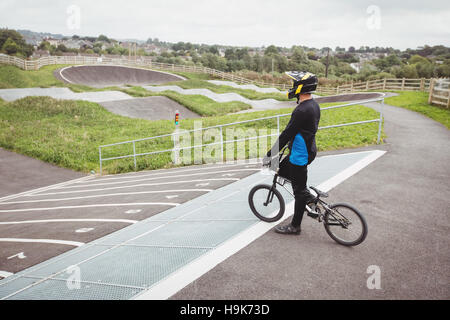 Ciclista in piedi con la BMX bike sulla rampa di partenza Foto Stock