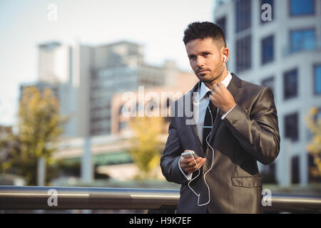 Imprenditore ascoltando la musica sul telefono cellulare Foto Stock