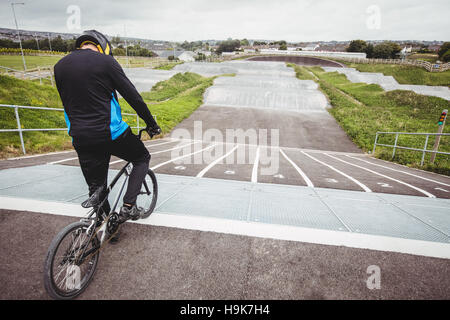 Ciclista in piedi con la BMX bike sulla rampa di partenza Foto Stock