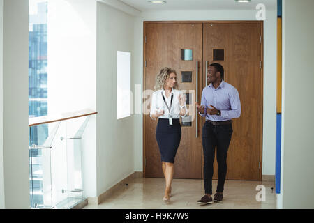 I dirigenti aziendali avente una discussione mentre si cammina nel corridoio Foto Stock