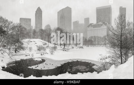 Congelato stagno e forte nevicata nel parco centrale con una vista panoramica di grattacieli di Manhattan. Midtown, New York City (B&W) Foto Stock