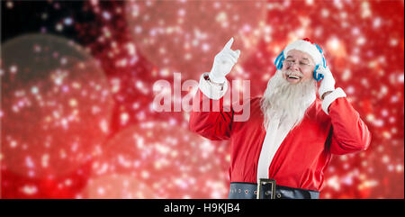 Immagine composita di santa claus ascoltando musica sulle cuffie Foto Stock