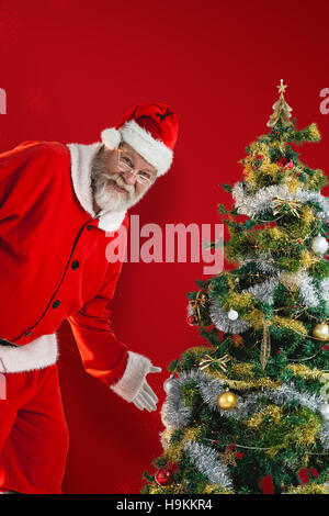 Immagine composita di santa claus toccando albero di natale Foto Stock