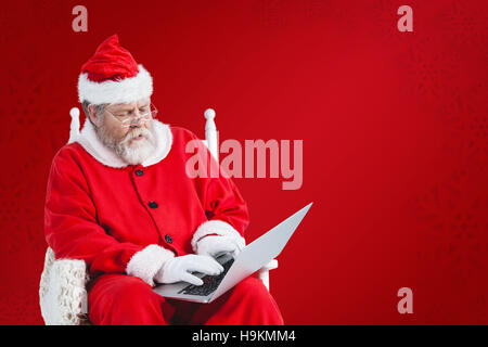 Immagine composita di grave santa claus utilizzando laptop Foto Stock