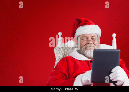 Immagine composita di close-up di santa claus azienda digitale compressa sulla poltrona Foto Stock