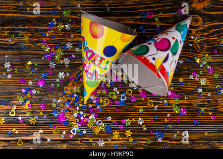 Vista dall'alto sui tappi di compleanno e colorata festosa confetti sono sparsi sulla scrivania in legno Foto Stock