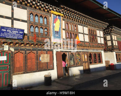 Il Bhutan negozi sulla strada principale nella capitale Thimpu con il re il ritratto sopra una delle porte e la bandiera nazionale. Foto Tony Gale