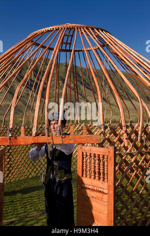 Uomo in abiti tradizionali di legatura del telaio in legno di un Yurt soggiornare in Kazakistan Foto Stock