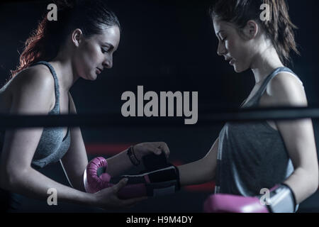 Donna aiutando boxer femmina mettendo su Boxe Guantoni boxe Foto Stock