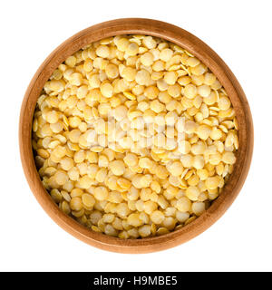 Lenticchie gialle in ciotola di legno su sfondo bianco. Semi di Lens culinaris, materie commestibili impulsi della famiglia del legume. Foto Stock