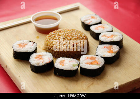 Phtograph di Sushi alcune fette di rotolo e riso fritto su una tavola di legno Foto Stock
