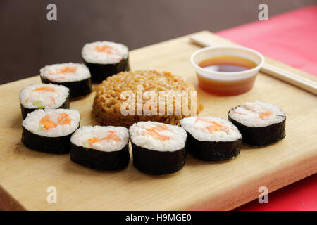 Phtograph di Sushi alcune fette di rotolo e riso fritto su una tavola di legno Foto Stock