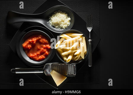 Penne la pasta con il sugo di pomodoro e formaggio parmigiano su sfondo nero Foto Stock