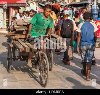 Uomo di legno portante sulla sua bicicletta rimorchio in Kathmandu Foto Stock