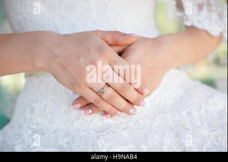 Mani sposa con anello in oro su sfondo di vestiti bianchi Foto Stock