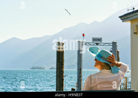 Ascona, Svizzera - Agosto 23, 2016: Senior signora seduta sul banco alla diga di Ascona resort di lusso sul lago Maggiore, Canton Ticino, Foto Stock