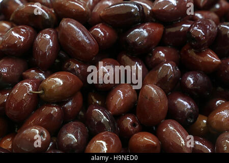 Kalamata Greco nero rosso lucido intero delle olive in olio vicino fino sfondo, sul mercato al dettaglio di stallo, display a basso angolo di visione Foto Stock