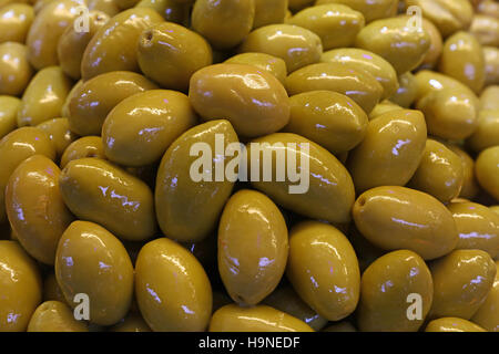 Verde intero grande olive italiane in olio vicino fino sfondo, mercato retail display di stallo Foto Stock
