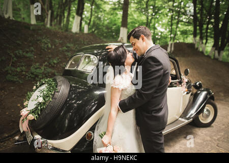 Bella sposa giovane in posa vicino retrò nero auto Foto Stock