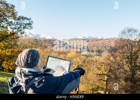 Donna che guarda la mappa e indicando che la strada da percorrere Foto Stock