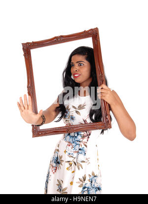 Una bella donna con lunghi capelli neri con in mano una cornice per foto in mano e raggiungendo il trogolo, isolato per sfondo bianco. Foto Stock