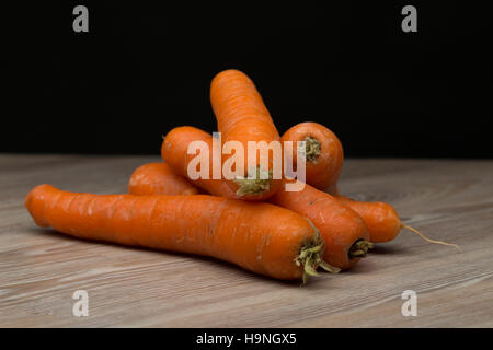 Pila di carote naturale in stile in legno lino, girato in studio, sfondo nero Foto Stock