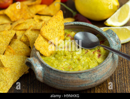 Guacamole in home predisposto sulla ciotola di legno naturale scrivania con paletta all'interno. Foto Stock