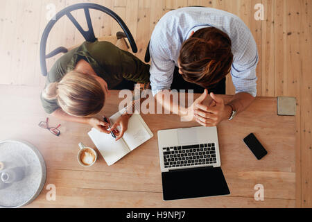 Vista dall'alto di un uomo e di una donna seduta a tavola e di lavoro. Due persone che lavorano insieme su laptop. Foto Stock
