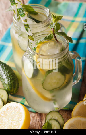 Bevanda estiva con il cetriolo, limone, ghiaccio e menta vicino fino in un barattolo di vetro sulla tavola verticale. Foto Stock