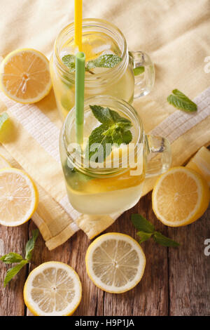 Limonata tradizionale con ghiaccio e menta vicino fino in un vasetto di vetro sul tavolo. vista verticale da sopra Foto Stock