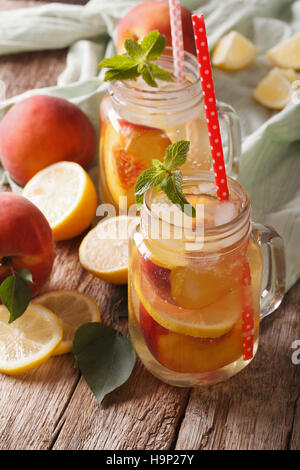 Pesche fresche limonata con ghiaccio e menta in un vasetto di vetro closeup sul piano verticale. Foto Stock