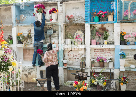 Una famiglia messicana organizza fiori sulla tomba di un relativo nella Nuestra Se-ora de Guadalupe cimitero durante il giorno dei morti festival il 1 novembre 2016 in San Miguel De Allende, Guanajuato, Messico. La settimana di festa è un momento in cui i messicani benvenuti i morti alla messa a terra per una visita e celebrare la vita. Foto Stock