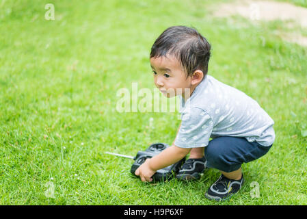 Little Asian kid tenendo un telecomando radio (controllo microtelefono per elicottero , fuco o piano presso il parco giochi, scuola cantiere. Capretto felice in kin Foto Stock