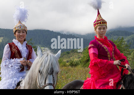 Ragazze kazake in costumi nazionali che cavalcano il loro cavallo ad Almaty, Kazakistan Foto Stock