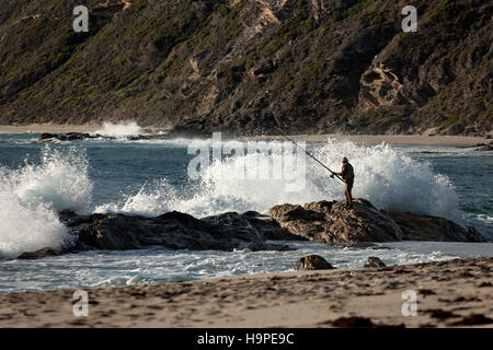 Un pescatore solitario in piedi su rocce con un'onda, Augusta Australia Occidentale Foto Stock