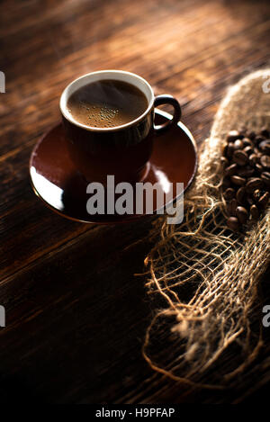 Tazza da caffè con piattino su un tavolo di legno. Sfondo scuro. Foto Stock